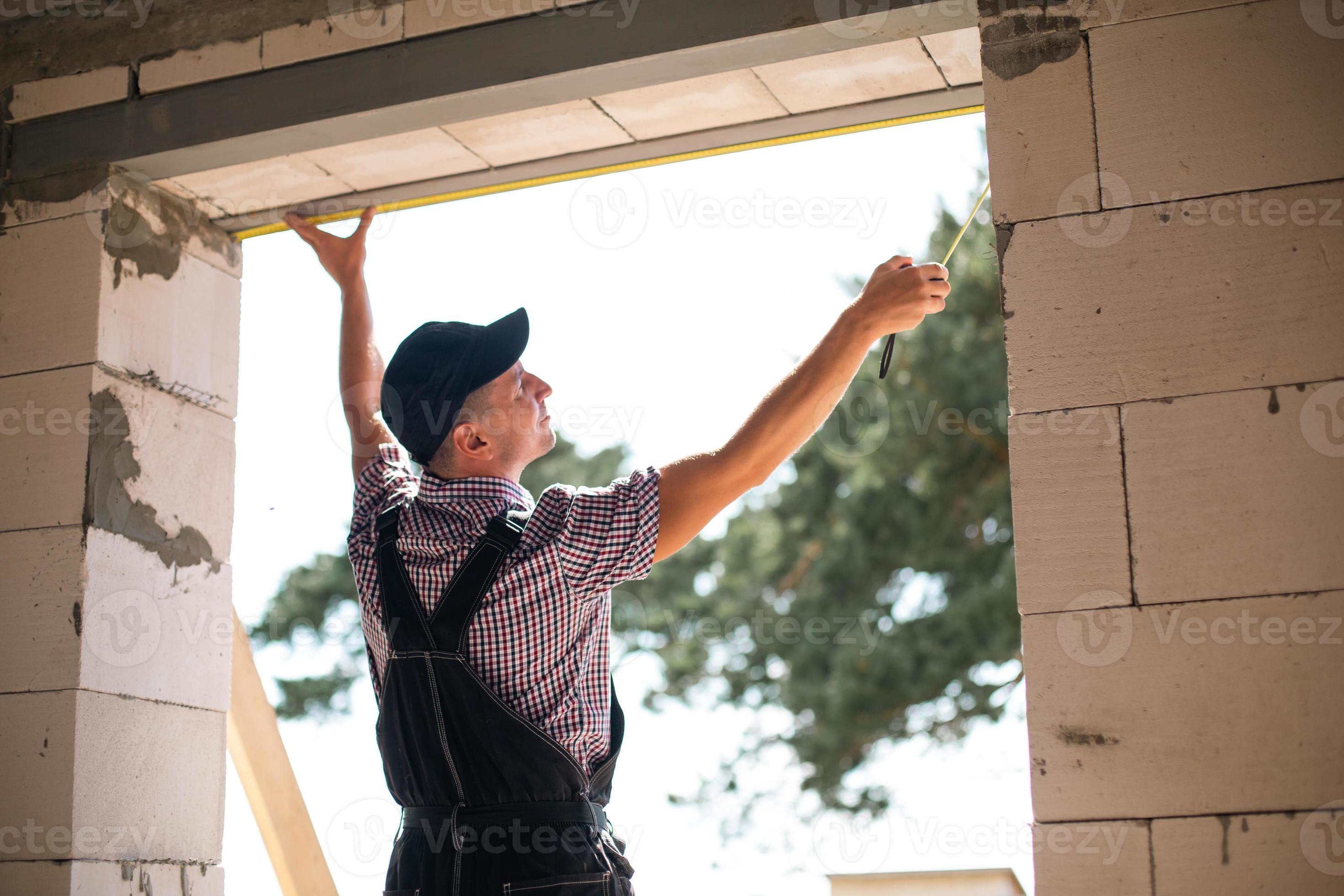 un ouvrier du bâtiment sur le chantier mesure la longueur de l