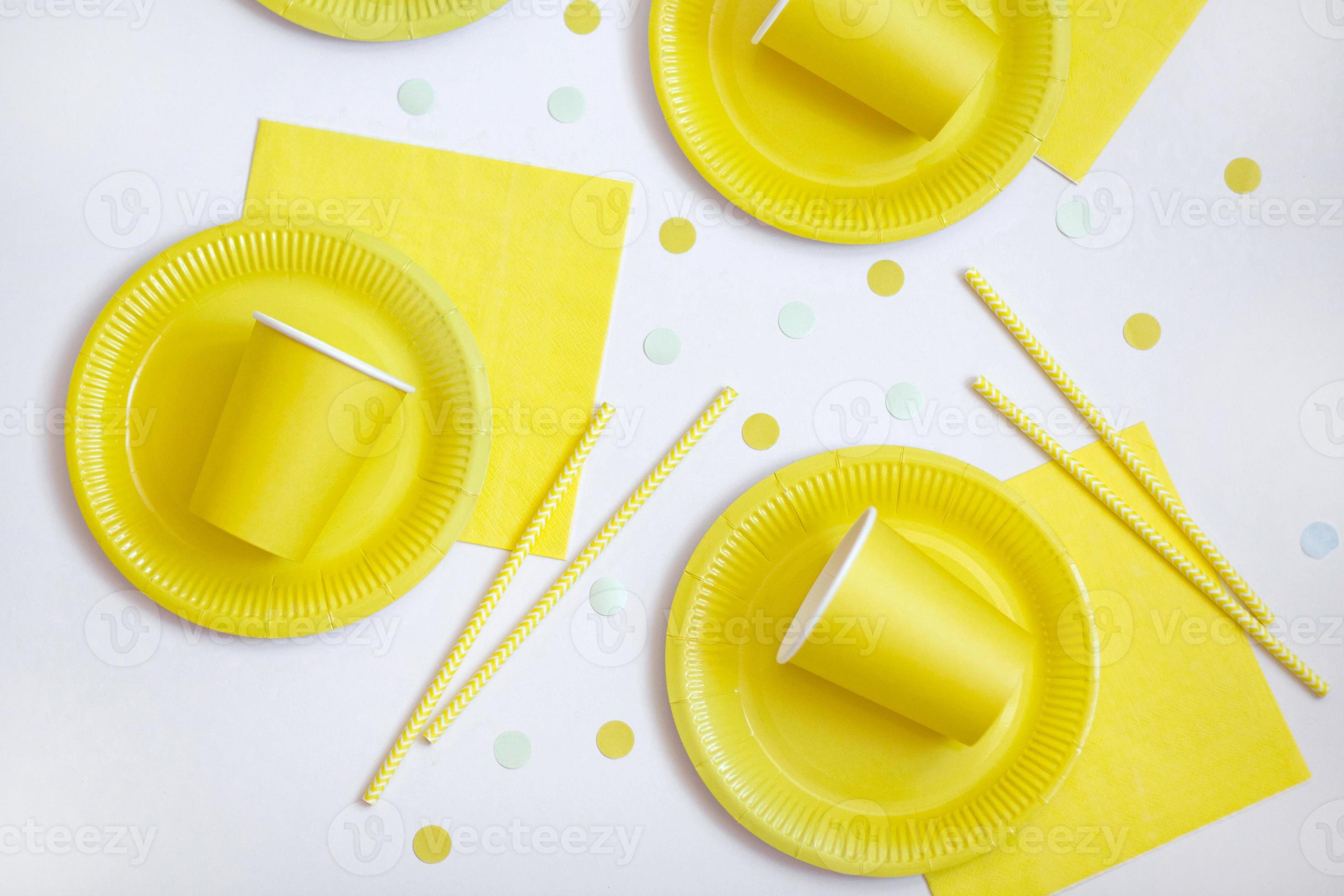 assiettes jetables en papier jaune, serviettes et pailles pour boissons sur  fond blanc. dressage de table pour pique-nique. éco-cour lumineuse. concept  d'anniversaire, de fête et de vacances. vue de dessus, mise à