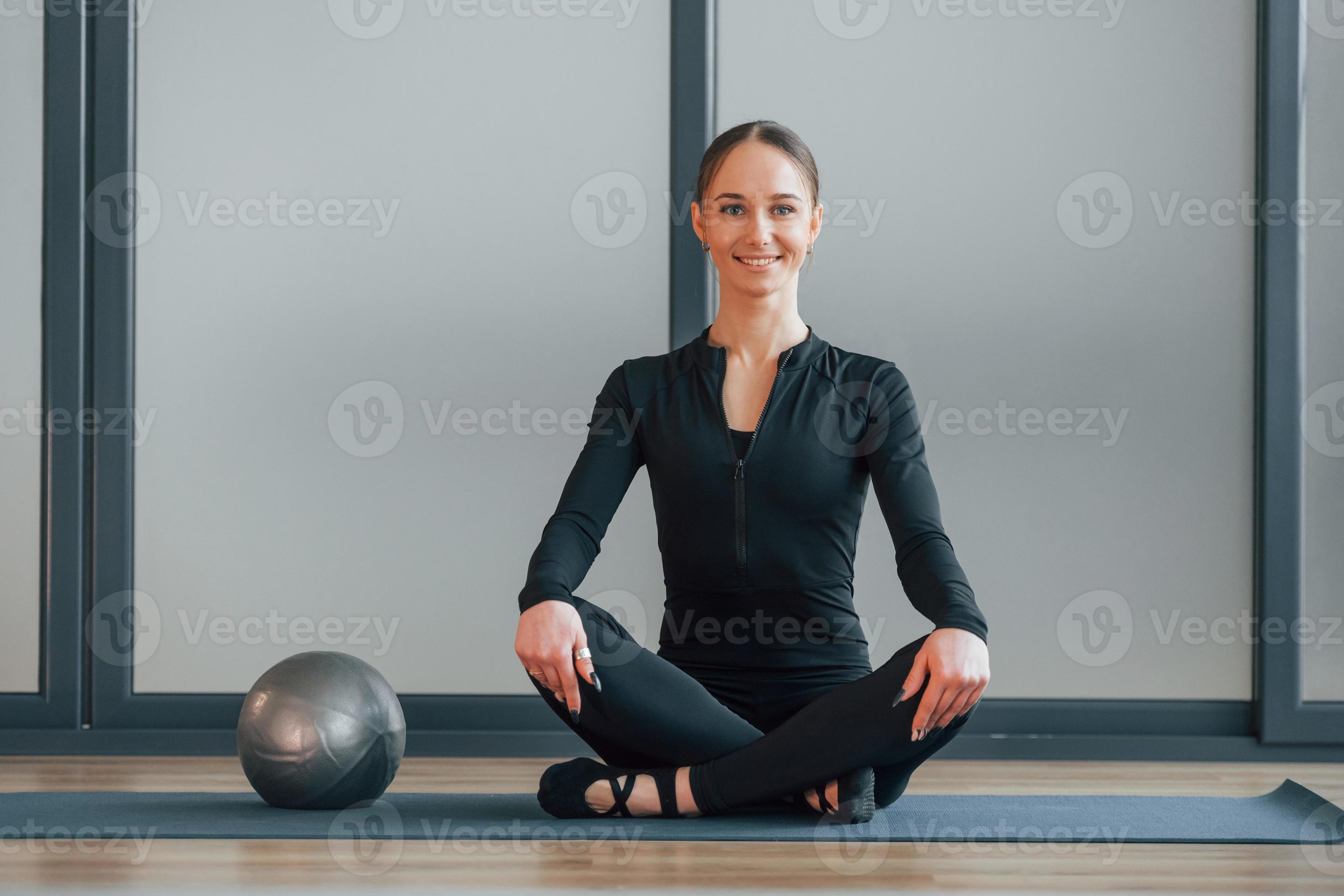 assis sur un tapis de yoga. femme en vêtements sportifs est en studio  8237967 Photo de stock chez Vecteezy