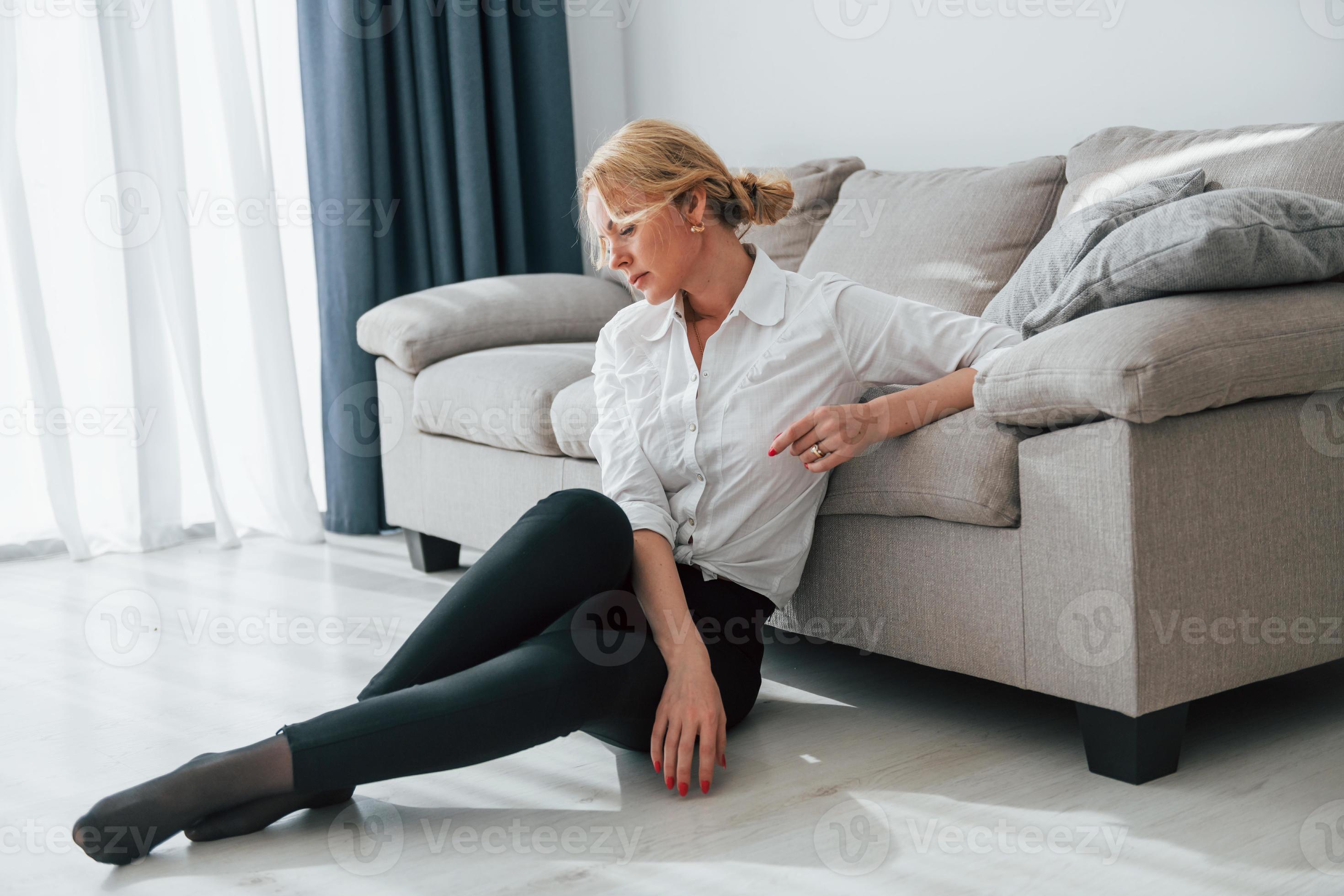 en jean noir. femme en tenue de soirée assise sur le sol près du canapé  dans la chambre domestique 8363126 Photo de stock chez Vecteezy