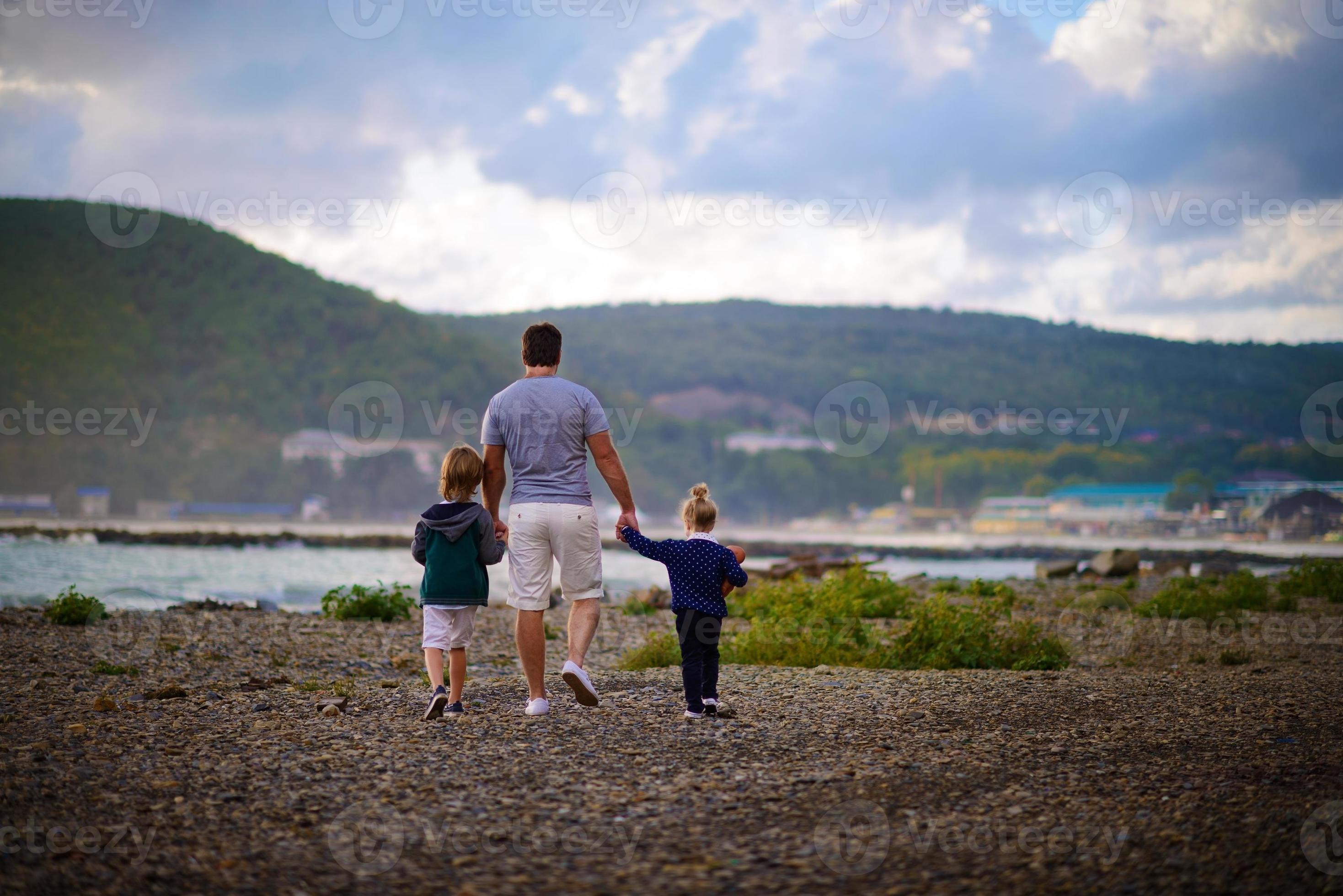 père marchant avec ses enfants le long de la plage photo