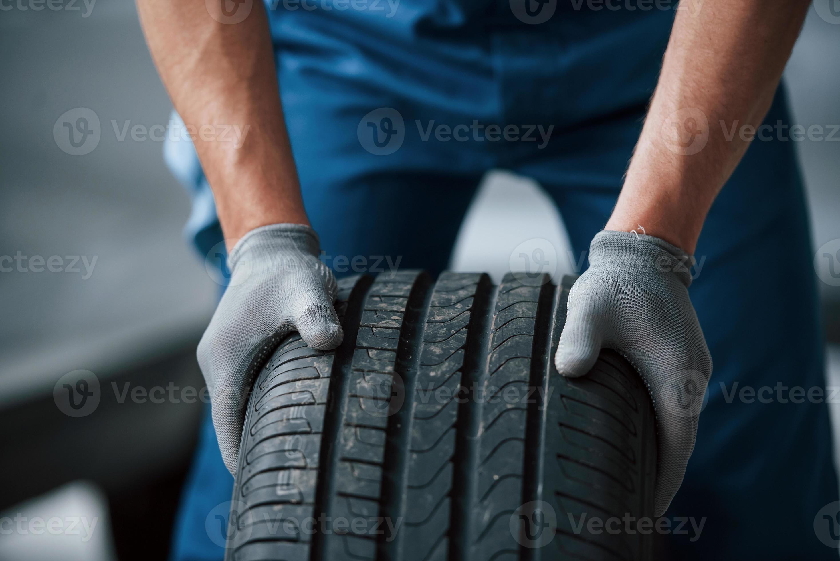 saleté sur la roue. mécanicien tenant un pneu au garage de réparation.  remplacement des pneus d'hiver et d'été 8681910 Photo de stock chez Vecteezy