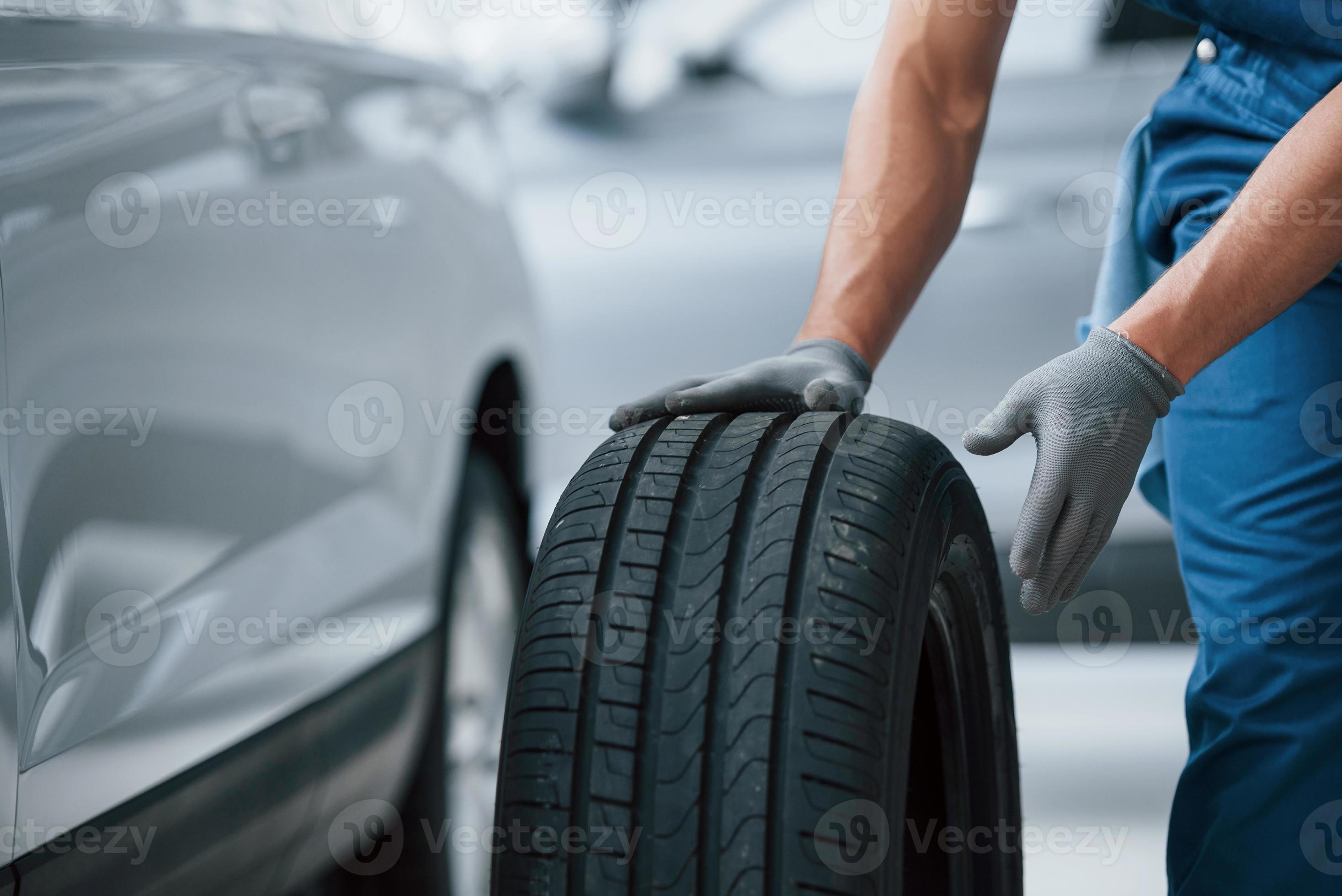 Je Reviens Tout De Suite. Mécanicien Tenant Un Pneu Au Garage De  Réparation. Remplacement Des Pneus Hiver Et été.