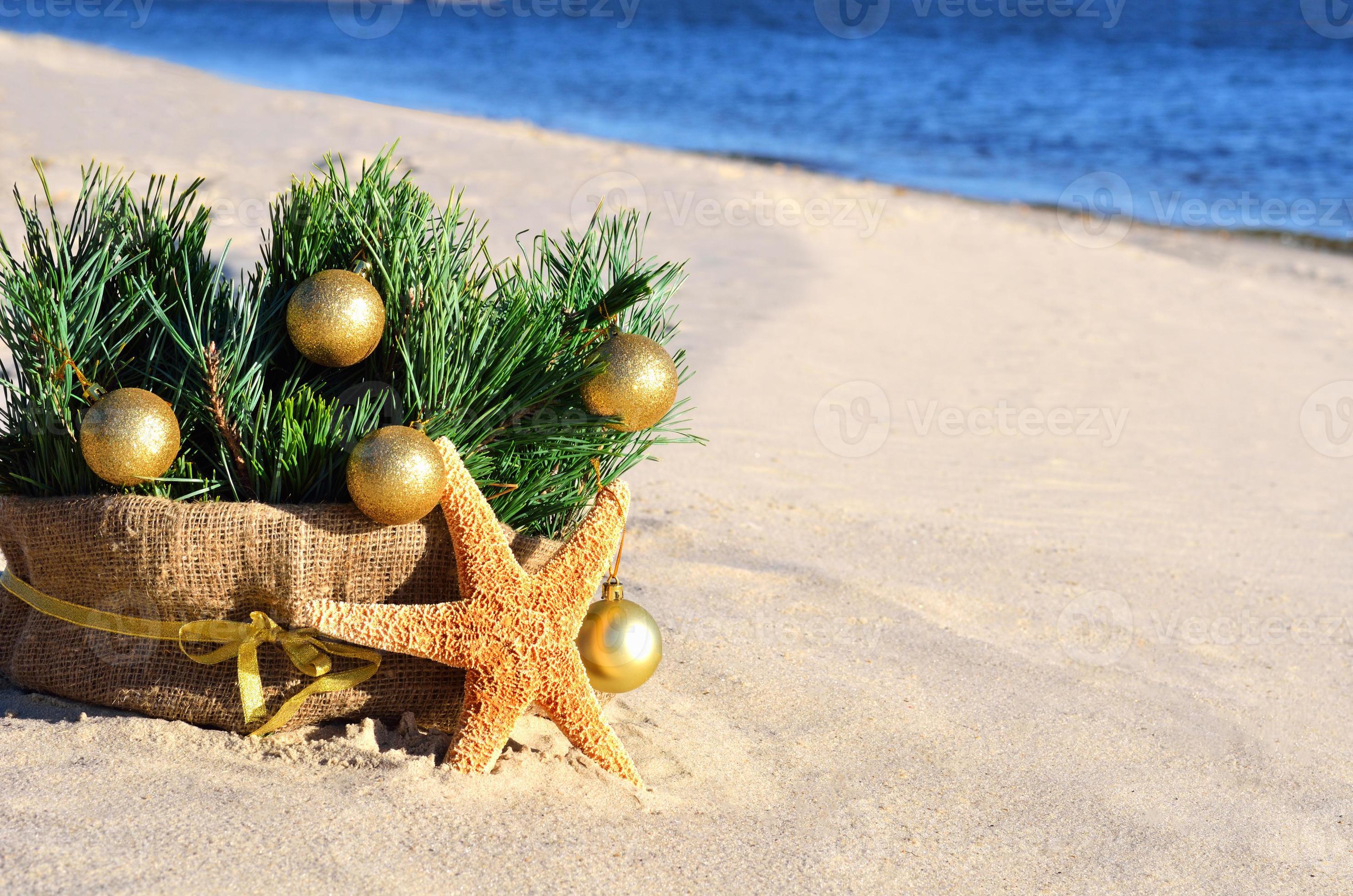 arbre de Noël avec des boules de Noël dorées, étoiles de mer sur le sable, plage photo