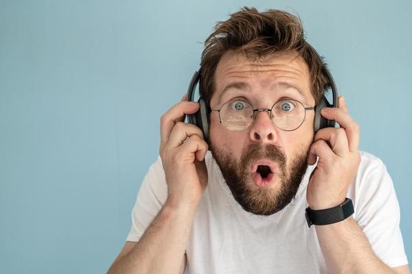 un homme barbu et hirsute au casque écoute de la musique, il est ennuyé et  surpris, il n'aime pas ce qu'il entend. fermer. 18775389 Photo de stock  chez Vecteezy