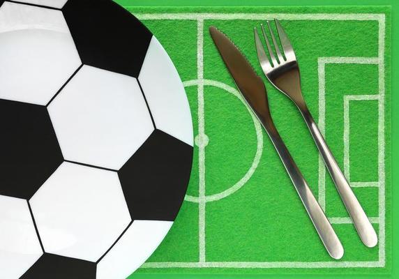 pop-corn sur une grande assiette peinte comme un ballon de football et un  tapis de vaisselle comme un terrain de football en feutre vert avec place  pour le texte. modèle de table
