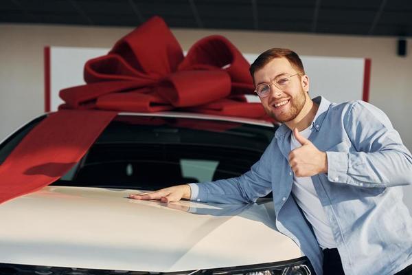 l'automobile est couverte de ruban cadeau. homme qui a réussi dans des  verres debout près d'une voiture neuve à l'intérieur 15363530 Photo de  stock chez Vecteezy