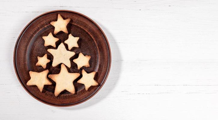 cuisson comme arbre de noël sur une plaque brune, biscuits en forme d'étoile,  noix, cannelle sur une table en bois blanche. 15473435 Photo de stock chez  Vecteezy