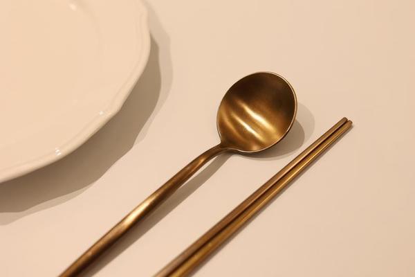 un ensemble de cuillère et de baguettes en laiton coréen avec un plat blanc  vide sur la table 17668377 Photo de stock chez Vecteezy