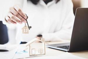 les agents immobiliers acceptent d'acheter une maison et remettent les clés aux clients dans les bureaux de leur agence. accord de concept. photo