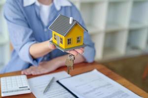 comptable, femme d'affaires, agent immobilier, femme d'affaires asiatique remettant une maison modèle et des clés aux clients ainsi que des documents de calcul des intérêts de la maison que les clients doivent signer photo