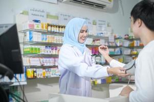 femme pharmacienne musulmane conseillant le client sur l'utilisation des médicaments dans une pharmacie de pharmacie moderne. photo