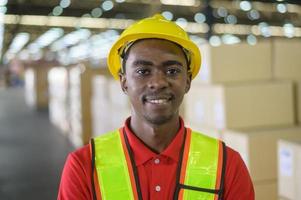 portrait d'un jeune travailleur masculin de race mixte portant un casque dans un entrepôt moderne d'un magasin de détail photo