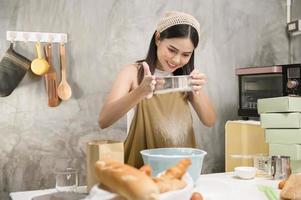 belle jeune femme cuisine dans sa cuisine, sa boulangerie et son café photo