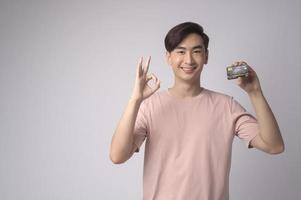 jeune homme asiatique tenant une carte de crédit sur fond blanc concept de studio, de shopping et de finance. photo