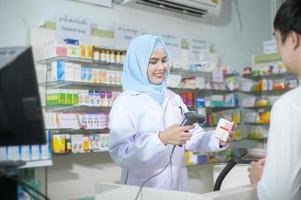 femme pharmacienne musulmane conseillant le client sur l'utilisation des médicaments dans une pharmacie de pharmacie moderne. photo