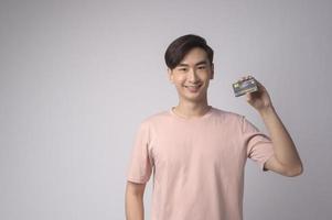 jeune homme asiatique tenant une carte de crédit sur fond blanc concept de studio, de shopping et de finance. photo