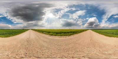 panorama hdri sphérique complet et harmonieux vue à 360 degrés sur la route de gravier parmi les champs en été avec des nuages impressionnants avant la tempête en projection équirectangulaire, pour le contenu de réalité virtuelle vr ar photo