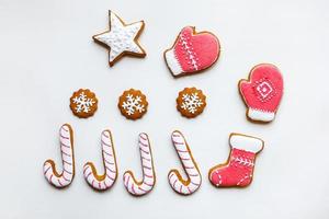 biscuits de pain d'épice festifs faits à la main sous forme d'étoiles, de flocons de neige, de personnes, de chaussettes, de personnel, de mitaines, d'arbres de noël, de coeurs pour les vacances de noël et du nouvel an sur fond de papier blanc photo