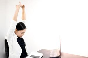 jeune asiatique se sentant douloureux du travail, assis devant l'ordinateur portable dans sa maison. concept syndrome de bureau de la femme qui travaille. photo