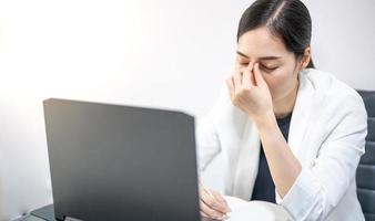 les jeunes asiatiques ressentent le stress du travail, assis devant l'ordinateur portable dans leur maison. photo