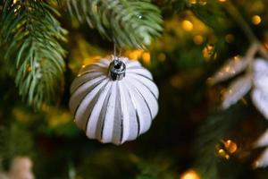 arbre de nouvel an décoré de noël classique. sapin de noël avec décorations blanches et argentées, jouet d'ornements et balle. appartement de design d'intérieur de style classique moderne. réveillon de noël à la maison. photo