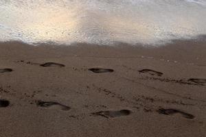 empreintes de pas dans le sable sur la plage de la ville. photo