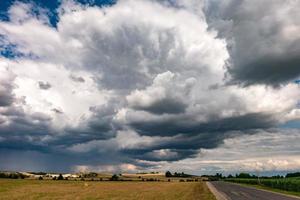 panorama hdr sur une route de gravier parmi les champs en soirée avec de superbes nuages noirs avant la tempête photo