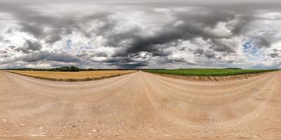 panorama hdri sphérique complet et harmonieux vue à 360 degrés sur la route de gravier parmi les champs avec des nuages impressionnants avant la tempête en projection équirectangulaire, prêt pour le contenu de réalité virtuelle vr ar photo