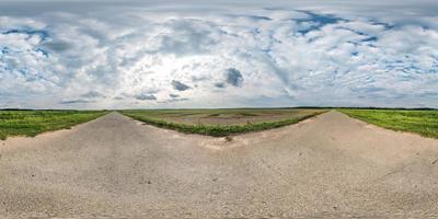 panorama sphérique complet et harmonieux à 360 par 180 degrés sur la route de gravier parmi les champs avec des nuages impressionnants en projection équirectangulaire, contenu de réalité virtuelle skybox vr photo