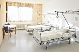 chambre d'hôpital avec deux lits et une table avec deux chaises