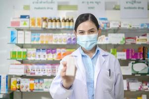 portrait d'une pharmacienne portant un masque facial dans une pharmacie de pharmacie moderne. photo