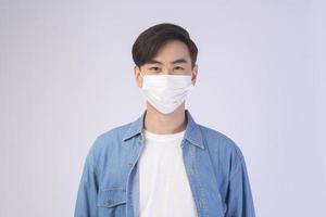 jeune homme asiatique portant un masque de protection sur fond blanc studio, voyage de sécurité, nouveau concept normal, distanciation sociale, covid19 et pandémie. photo