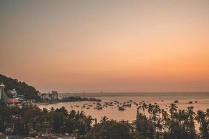 vue aérienne de la ville de vung tau avec un beau coucher de soleil et tant de bateaux. vue panoramique sur la côte vung tau d'en haut, avec vagues, littoral, rues, cocotiers et montagne tao phung au vietnam. photo