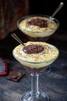 pudding à la vanille et au chocolat dans un grand verre avec des morceaux de chocolat râpés photo