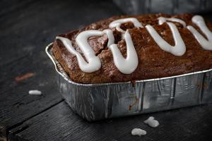 Pain de pain aux noix de pécan à la citrouille avec glaçage au sucre sur une table en bois foncé photo