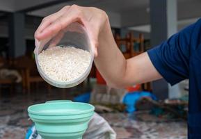 la femme remplit les grains de riz dans une bouteille en plastique par un entonnoir. versez le riz dans une bouteille jusqu'à ce que vous soyez prêt à l'utiliser. photo