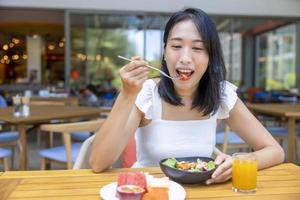 femme prenant son petit déjeuner. fruits comme la pastèque, la papaye, le melon, le fruit de la passion, le jus d'orange et le café. posé sur un napperon gris photo