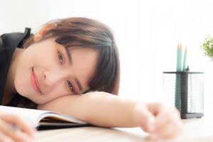 beau portrait jeune femme asiatique sourire et bonne écriture examen d'apprentissage ou devoirs et couché avec bureau, mode de vie beauté asie fille avec travail, éducation et concept d'entreprise. photo