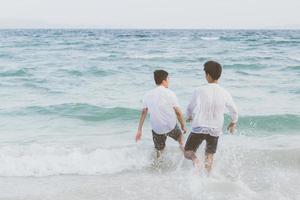 portrait homosexuel jeune couple asiatique courant avec gai ensemble sur la plage en été, asie gay faisant du tourisme pour les loisirs et se détendre avec bonheur en vacances en mer, concept juridique lgbt. photo