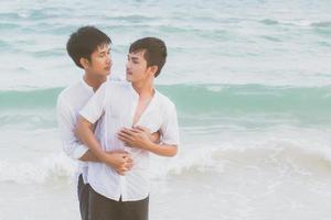 portrait homosexuel jeune couple asiatique debout câlin et regarder ensemble sur la plage en été, asie gay faisant du tourisme pour les loisirs et se détendre avec romantique et heureux en vacances en mer, concept juridique lgbt. photo