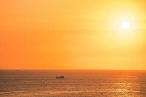 beau paysage de plage au coucher du soleil, nature exotique de l'île tropicale, ciel rouge jaune coloré, bateau silhouette, reflet doré du soleil, vacances d'été. cinématique de nuage de ciel. photo