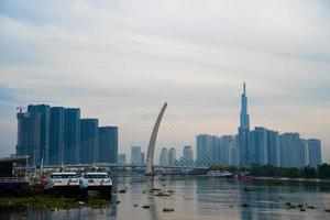 ho chi minh ville, vietnam - 12 février 2022 skyline avec le gratte-ciel historique 81, un nouveau pont à haubans est en train de construire reliant la péninsule de thu thiem et le district 1 de l'autre côté de la rivière saigon. photo