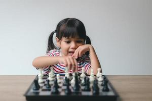 petite fille asiatique jouant aux échecs à la maison.une partie d'échecs photo