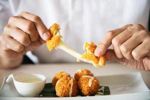 l'homme va manger une boule de fromage frit collante. la photo est centrée sur la boule de fromage