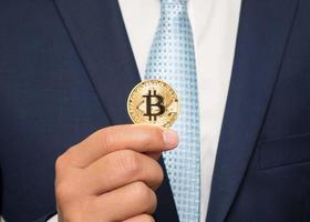 homme d'affaires en costume tenant un bitcoin doré photo