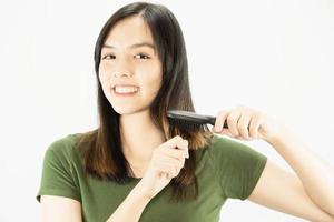 jeune belle dame heureuse à l'aide d'un peigne pour redresser ses cheveux - concept de soins capillaires beauté femme photo