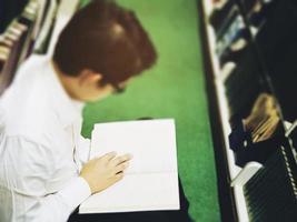 un homme lit un livre près de la bibliothèque de la bibliothèque photo