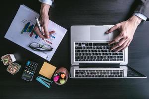 vue de dessus d'homme d'affaires utilisant un ordinateur portable avec analyse des graphiques d'investissement sur le bureau. photo