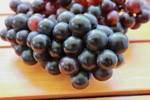 grappes de raisins violets mûrs sur fond en bois. tas de raisins rouges et noirs frais en arrière-plan. fruits de santé photo